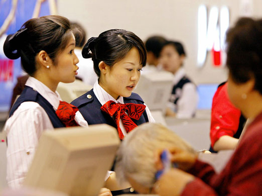 Japan Airlines: Japan Airlines System ground staff help customers at the luggage check-in 