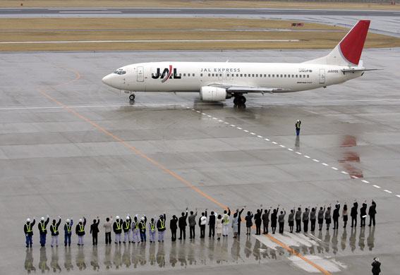 Japan Airlines: Japan Airlines workers wave at one of their planes preparing for take off