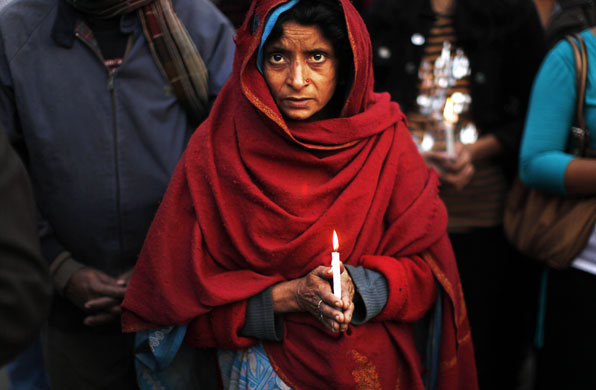 24 hours in pictures: New Delhi, India: A woman holds a candle at an inter-faith prayer service
