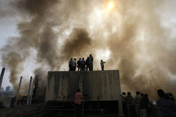 24 hours in pictures: Mumbai, India: Local residents watch firemen dousing a fire