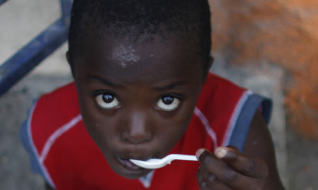 A Haitian child eats a free meal received from a local restaurant in Port-au-Prince