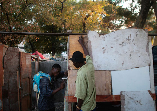 Camps in Haiti: Displaced Haitians hammer together wood scraps to make rooms in a  camp