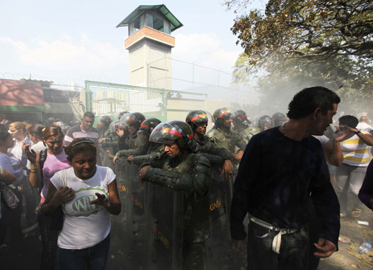 24 hours in pictures: Caracas: Relatives of inmates walk around a barrier of National Guard