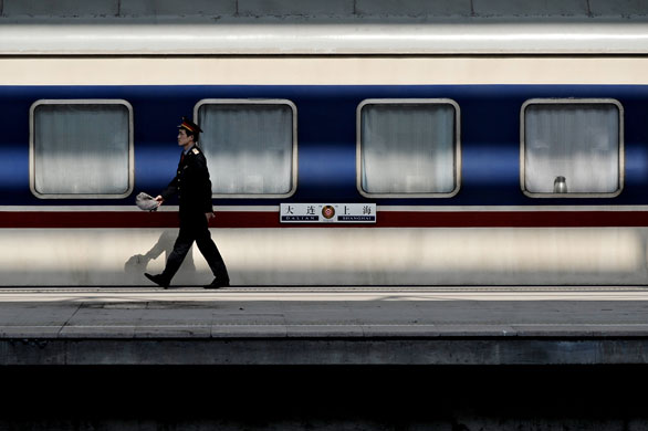 24 hours in pictures: Shanghai, China: A railway employee walks alongside a train