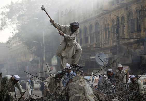 24 hours: Karachi, Pakistan: A labourer clears rubble at the site of destroyed shops