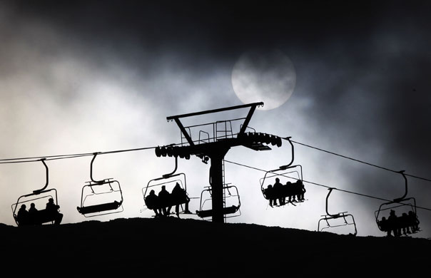 24 Hours in Pictures: Skiers sit in a chair lift silhouetted by the sun in Seefeld, Austria