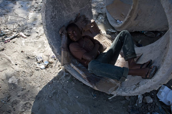 24 hours in pictures: A man rests in a concrete cylinder on a street in Carrefour, Port-au-Prince
