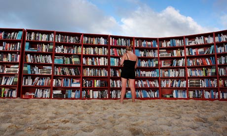 A beach goer selects books from world's longest outdoor bookcase on Bondi Beach, Sydney, Australia