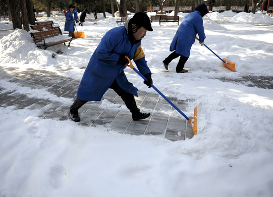 snow in korea and china: Beijing, China: Workers shovels snow to clear  Jinshan park