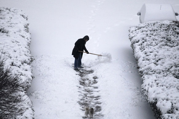 snow in korea and china: A man shovels snow on a street in Yantai