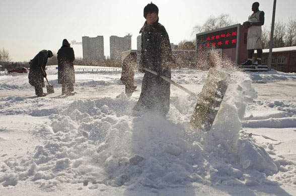 snow in korea and china: Beijing, China: Security workers shovel snow in a parking lot 