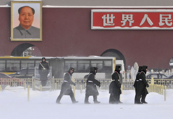 snow in korea and china: Paramilitary policemen walk in a snow covered Tiananmen Square in Beijing