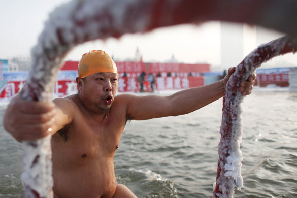 24 hours in pictures: Harbin, China: A swimmer climbs out of the icy waters of the Songgua river
