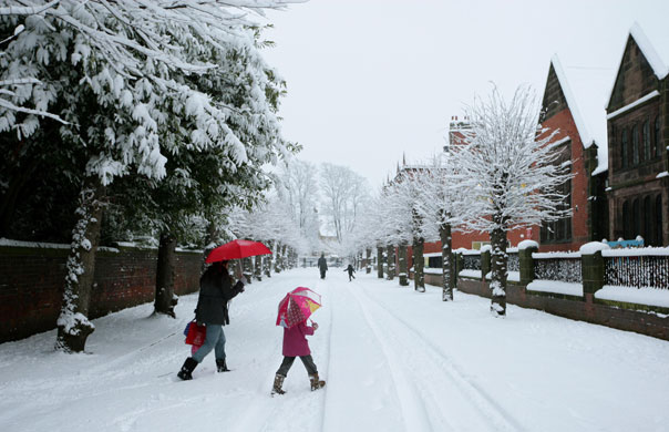 UK weather update: Pedestrians cross a street in Stockport following heavy overnight snow