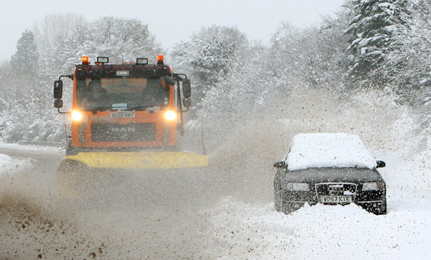 Winter weather: Hampshire: A snowplough passes an abandoned car on the A3