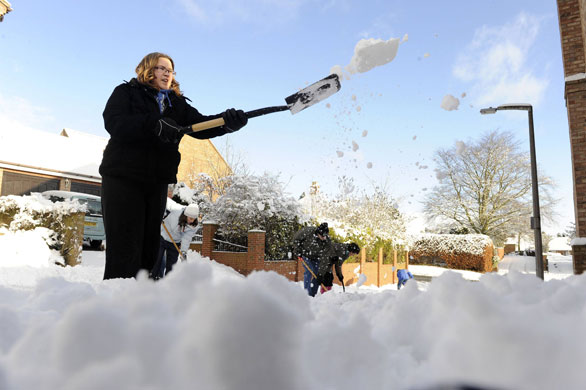 Winter weather: Kirby Hill, North Yorkshire: A woman clears snow from a road