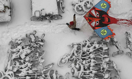 A child flies a kite over snow-covered bicycles in Beijing, China.