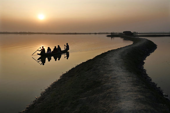 24 hours in pictures: Bangladeshi boatmen carry passenger in a canal at Mithakhail