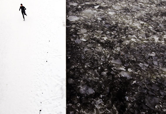 24 Hours in Pictures: A woman runs along the snow covered banks of the Spree river in Berlin