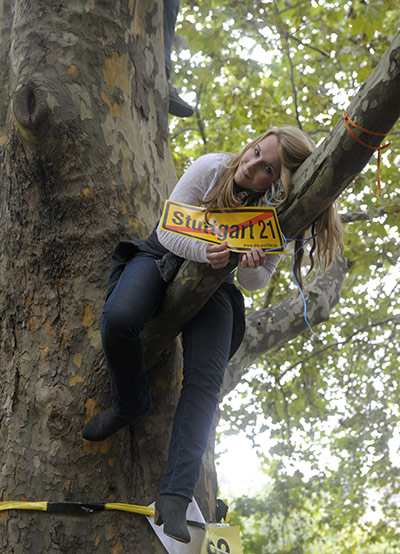 Stuttgart 21 Protest: Protestor sits in a tree showing a protest banner for Stuttgart 21