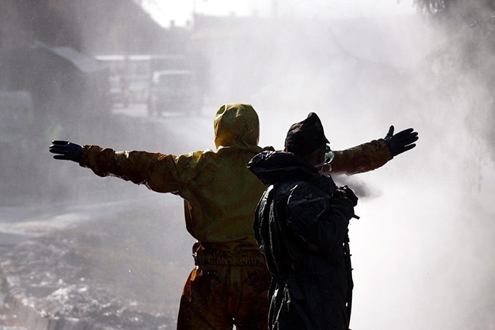 Hungary toxic sludge: Hungarian soldiers wearing protective gear are washed by water jets