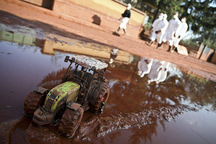 24 hours: Rescue workers walk past a toy tractor covered with red toxic sludge