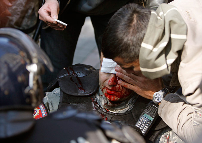 24 hours: Riot policemen help a colleague injured during clashes in Belgrade