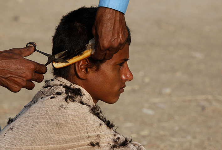 24 hours in pictures: Dadu, Pakistan: A boy gets his hair cut in a camp
