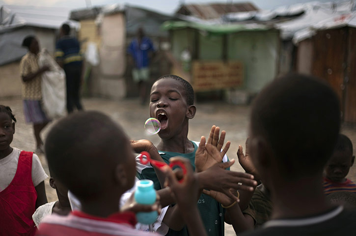 Ramon Espinosa: Children play with soap bubbles in a camp set up  for earthquake victims