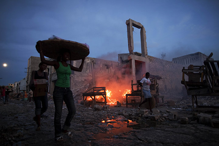 Ramon Espinosa: People walk past remains of buildings destroyed by the January earthquake