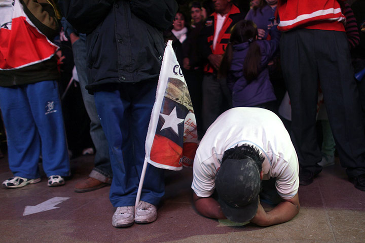 chile miners rescued: A man prays on his knees while watching on the rescue on TV at the mine 