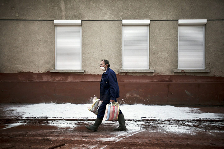 24 hours: A local citizen wears a protective mask as he walks though toxic red sludge