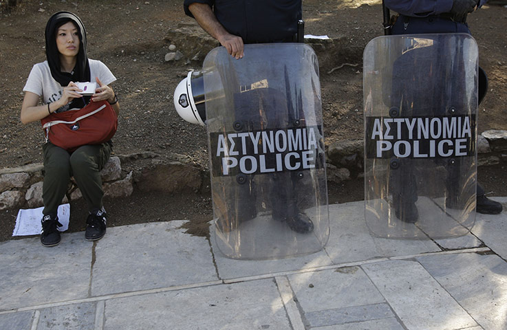 24hours: A tourist sits next to riot police guarding the entrance to the Acropolis 