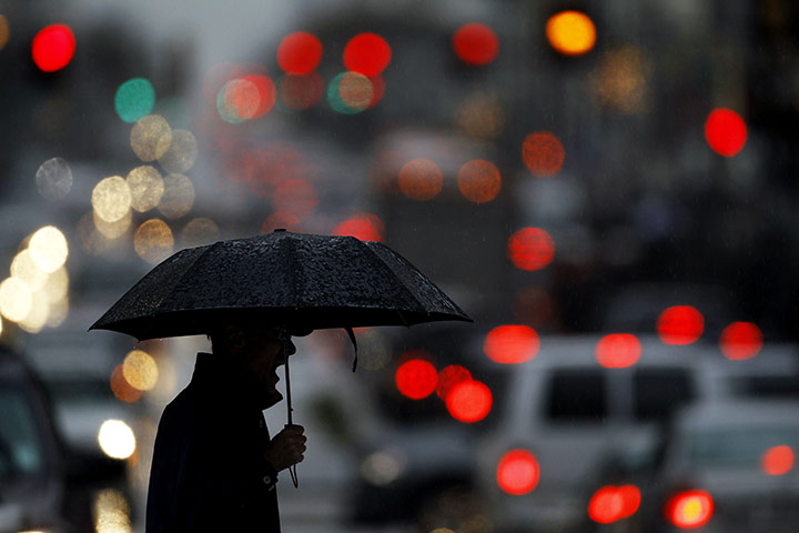 24hours: Philadelphia, a person waits to cross street during an afternoon rainstorm