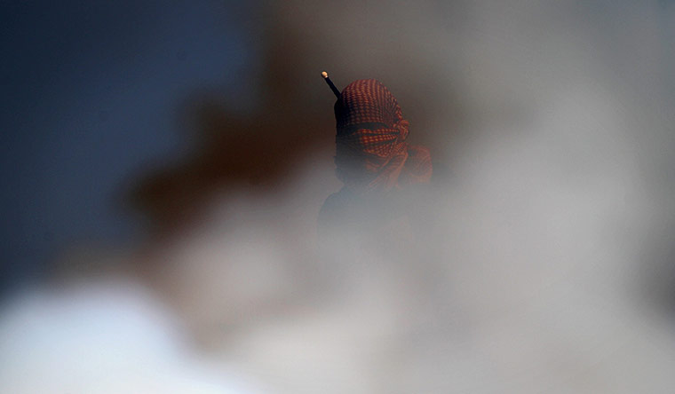 24 Hours in Pictures: A Palestinian man wearing a kefiah stands amid a cloud of teargas