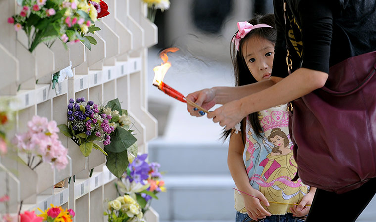 24 hours in pictures: Hong Kong, China: A little girl and her mother light candles and incense