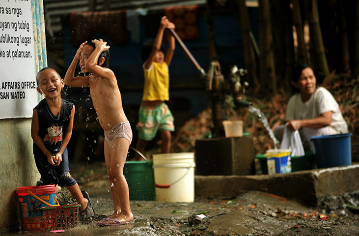 typoon: Children wash themselves at their home under a bridge in Manila