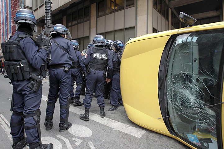 Fuel shortages in France: Riot policemen stand near a damaged car after rioting in Lyon