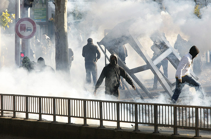Fuel shortages in France: Youth walk away from a damaged phone booth during clashes in Nanterre