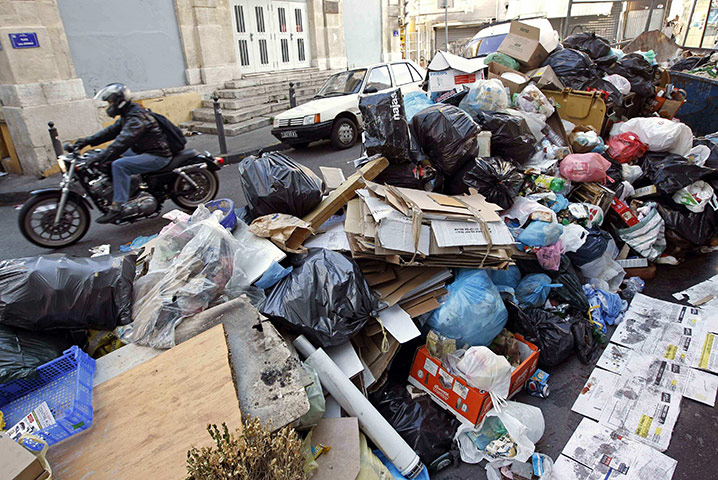 Fuel shortages in France: A man on a motorcycle rides past a pile of garbage in Marseille