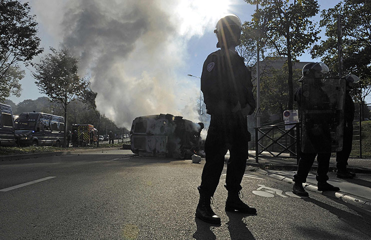 Fuel shortages in France: Police stand near a burning van after rioting during a student demo