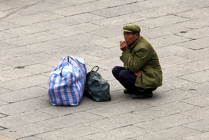 24 hours: Beijing, China: A migrant worker crouches next to his belongings