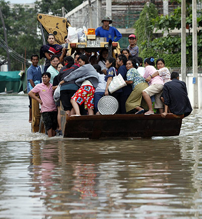24 hours: Thailand: Residents ride on a loader as it drives down a flooded road 