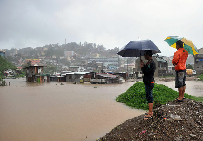 Typhoon Megi : Residents stand as rain lashes down on their homes submerged by flooding