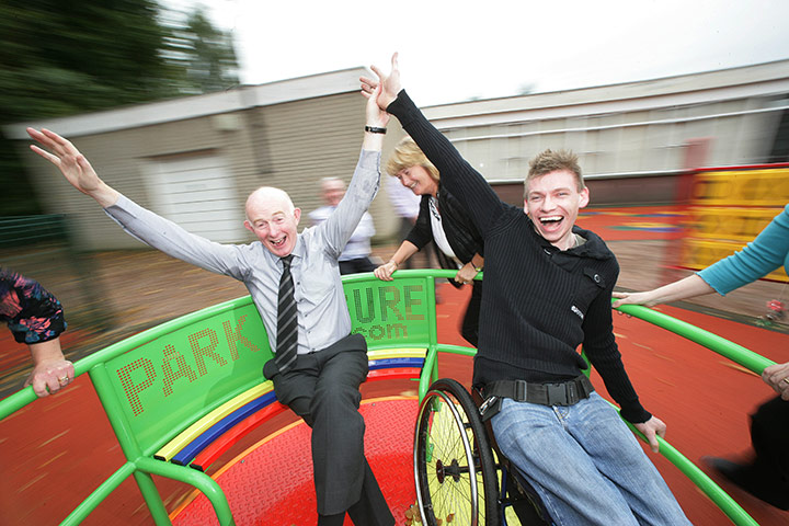 Teaching Awards 2010: A teacher and his student in a wheelchair enjoy a ride on a roundabout