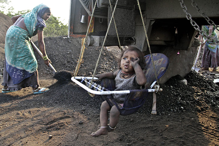 24 hours in pictures: A child of a labourer sits in a cradle at a coal warehouse
