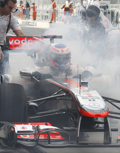 Korean Grand Prix: Jenson Button climbs out of his car as his pit crew use fire extinguishers