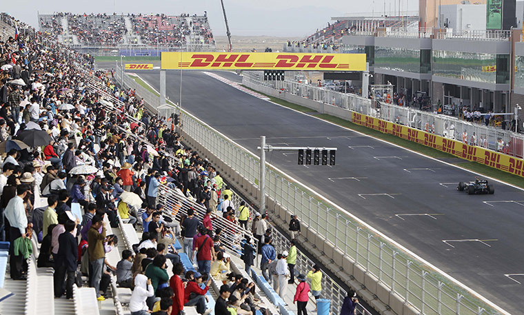 Korean Grand Prix: Fans in the main stand watch as Michael Schumacher drives past