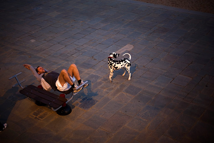 24 hours: A man exercises next to his dog in a park near to the beach in Barcelona