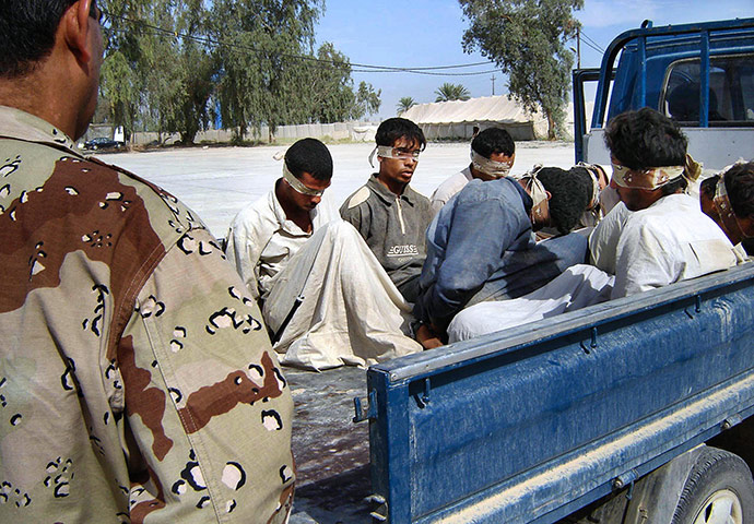 A Day in Iraq: An Iraqi army soldier guards blindfolded